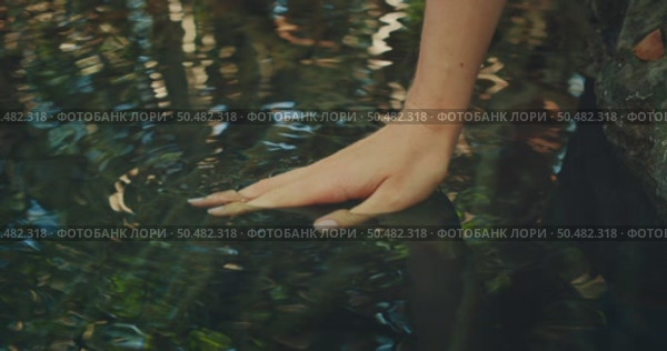 A hand barely touches the surface of a clear rippling pool of cenote in the jungle of Yucatan Mexico. Стоковое видео, видеограф Igor Tichonow / Фотобанк Лори