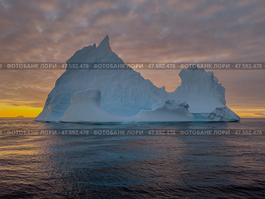 A huge high breakaway glacier drifts in the southern ocean off the coast of Antarctica at sunset, the Antarctic Peninsula, the Southern Arctic Circle, azure water, cloudy weather. Стоковое фото, фотограф Vladimir Drozdin / Фотобанк Лори