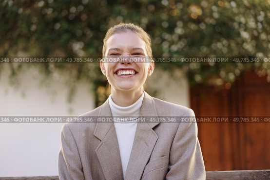 A joyful and energetic young woman dressed in a chic and fashionable outfit, proudly showcasing a bright and radiant smile set against a softfocus nature backdrop that enhances her cheerful demeanor. A Smiling Young Woman in a Stylish Outfit Poses Gracefully Against a Natural Background. Стоковое фото, агентство Ingram Publishing / Фотобанк Лори