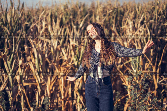 A joyful young woman delightfully poses amidst a lush, expansive cornfield, radiating pure happiness and a profound connection with the beauty of nature all around her on that sunny day. A Joyful Moment in a Beautiful Cornfield on a Bright and Sunny Day Filled with Fun and Energy. Стоковое фото, агентство Ingram Publishing / Фотобанк Лори