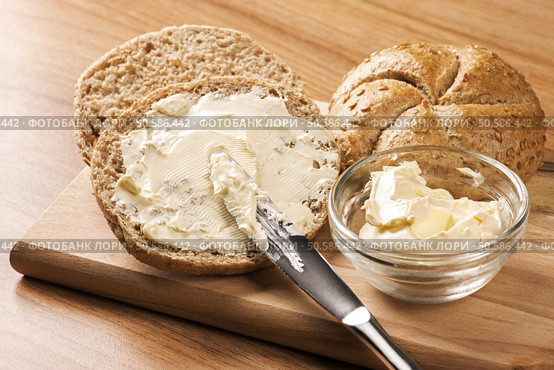A knife spreading butter on bread. Стоковое фото, агентство Ingram Publishing / Фотобанк Лори