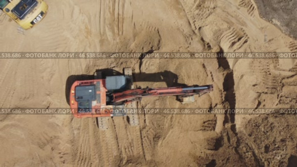A large orange excavator is digging into a sandy area. Стоковое видео, видеограф Скрипачев Антон / Фотобанк Лори