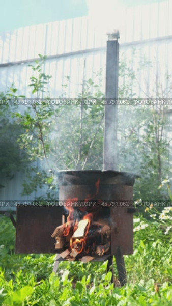 A lit fire with wood in the stove for cooking pilaf outside. Small iron stove with a chimney outside. Стоковое видео, видеограф Кашапова Эльвира / Фотобанк Лори