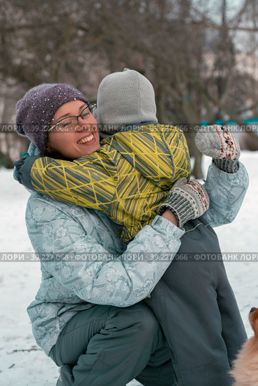A little boy in a winter jumpsuit hugs his mother on a walk. Стоковое фото, фотограф Ярославский Максим / Фотобанк Лори