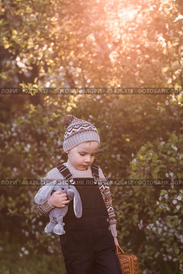 A little boy of 4 years old outdoors with a suitcase and a stuffed rabbit goes on a journey. A beautiful portrait of a child playing on the street. Стоковое фото, фотограф Photojuli / Фотобанк Лори