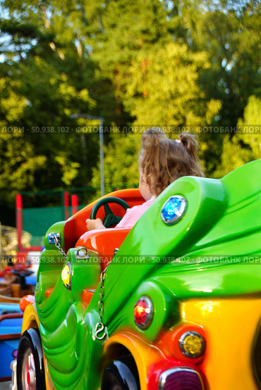 A little girl rides a green ride in a summer park. Russia. Moscow. 25.07.25. Редакционное фото, фотограф Ярославский Максим / Фотобанк Лори