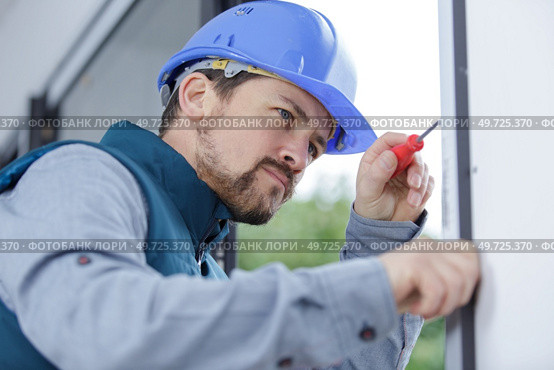 a man builder fixes a window. Стоковое фото, агентство Ingram Publishing / Фотобанк Лори
