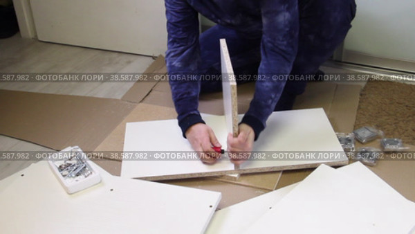 A man connects the panels with an eccentric. Wooden modular rack. Assembling a modular rack. Overall plan. Стоковое видео, видеограф Vadzim Yakubovich / Фотобанк Лори