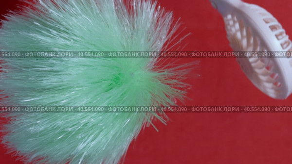 A man demonstrating the power of the airflow of a portable fan. Blows them a brush from different sides. On a coral background. Close-up. Стоковое видео, видеограф Vadzim Yakubovich / Фотобанк Лори