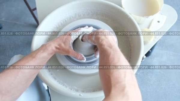 A man dries a white clay product with a hair dryer on a potter's wheel. Craft, creativity, the process of working on a potter's wheel. Стоковое видео, видеограф Терехова Марина / Фотобанк Лори