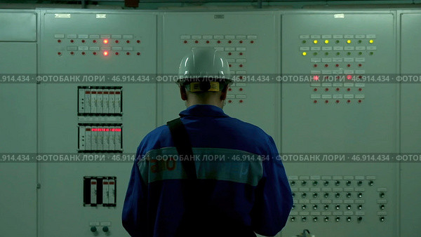 A man in a blue suit and a white helmet is trying to open special electrical equipment for work. Стоковое фото, фотограф David Kashakhi / Фотобанк Лори