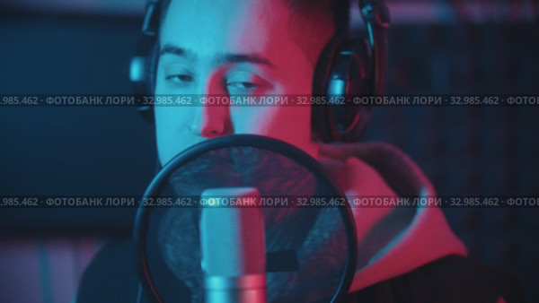 A man in hoodie rapping through the pop-filter in the microphone. Стоковое видео, видеограф Константин Шишкин / Фотобанк Лори