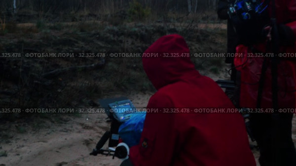A man in red jacket holding a camera and filming cinema scene in the forest. Стоковое видео, видеограф Константин Шишкин / Фотобанк Лори