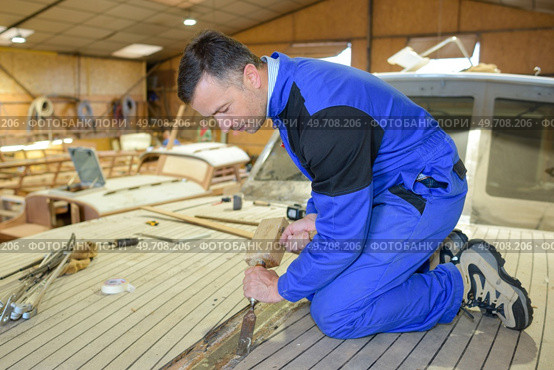 a man is disassembling a boat. Стоковое фото, агентство Ingram Publishing / Фотобанк Лори