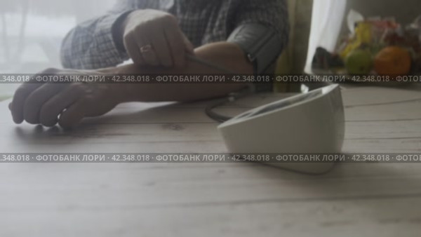 A man sits down at a table and measures blood pressure with a blood pressure monitor. Стоковое видео, видеограф Ярославский Максим / Фотобанк Лори