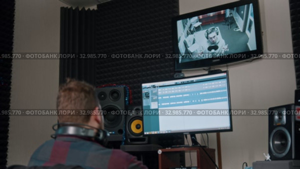 A man sound engineer recording audio tracks for a young man rapper. Стоковое видео, видеограф Константин Шишкин / Фотобанк Лори