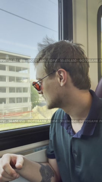 A man wearing sunglasses and a black shirt is sitting on a train. Стоковое видео, видеограф Ярославский Максим / Фотобанк Лори