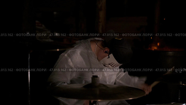 A masked man impulsively plays drums around a beautiful fireplace. Стоковое фото, фотограф David Kashakhi / Фотобанк Лори