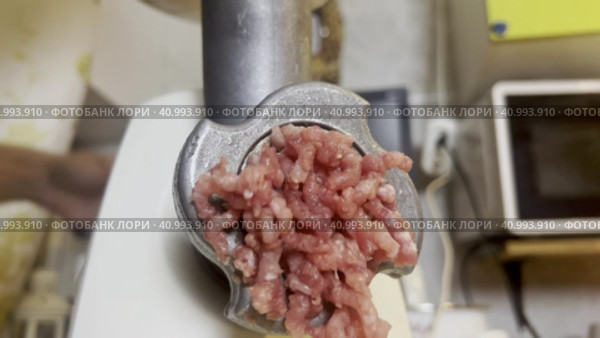 A meat grinder for chopping fresh raw meat works against the background of the kitchen.  Focus on a working meat grinder. Стоковое видео, видеограф Ярославский Максим / Фотобанк Лори
