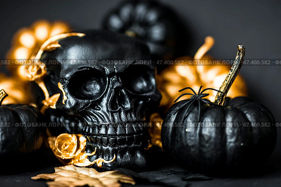 A mysterious black skull with golden roses and pumpkins for a Halloween or Day of the dead party on a black grunge background. Стоковое фото, фотограф Photojuli / Фотобанк Лори