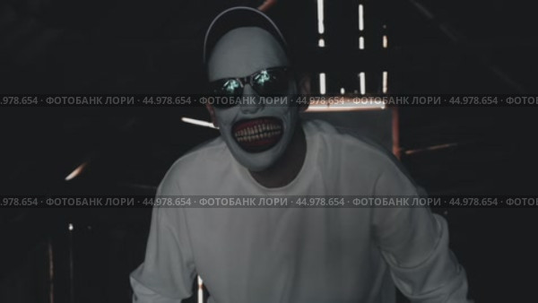 A pale-faced creature with sunglasses and a wide grinning mouth. An attic monster in a white sweatshirt and baseball cap in a dim room with rays of light coming through the cracks. Стоковое видео, видеограф Воловодов Владимир / Фотобанк Лори