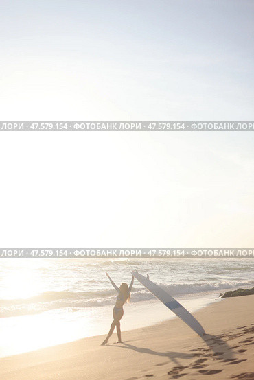 A person is standing on a sandy beach while holding a surfboard. Стоковое фото, фотограф Женя Канашкин / Фотобанк Лори