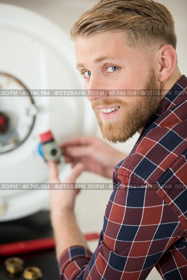 a professional electrician man is fixing a water heater. Стоковое фото, агентство Ingram Publishing / Фотобанк Лори