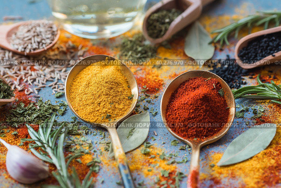 A set of fragrant spices. Turmeric, paprika, dried parsley, dill, rosemary, cumin, garlic, bay leaf and a bottle of oil on a gray background. Free space. Стоковое фото, фотограф Photojuli / Фотобанк Лори