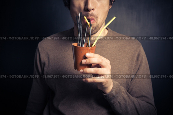 A silly young man is drinking from a leather cup with a bunch of colorful straws. Стоковое фото, агентство Ingram Publishing / Фотобанк Лори