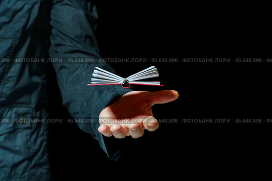 A small book levitates over a person's palm against a dark background. Стоковое фото, фотограф Татьяна Степанищева / Фотобанк Лори