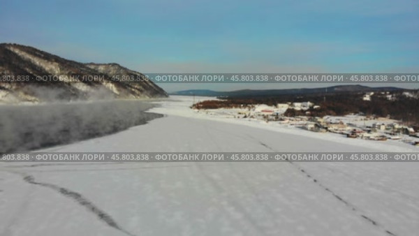 A snow-covered landscape with a river open in winter weather, near a remote village. Aerial view. Стоковое видео, видеограф Виктория Тельминова / Фотобанк Лори