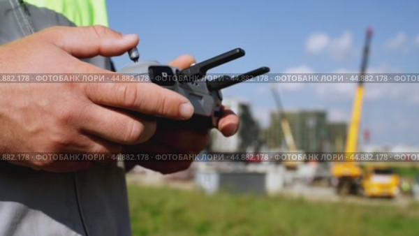 a surveyor on a construction site controls a quadcopter. Стоковое видео, видеограф Igor Skripachev / Фотобанк Лори