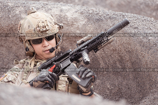 A Taliban soldier stands with a machine gun, Surrender to the allied soldiers, In the desert mountain terrain battlefield. Стоковое фото, агентство Ingram Publishing / Фотобанк Лори