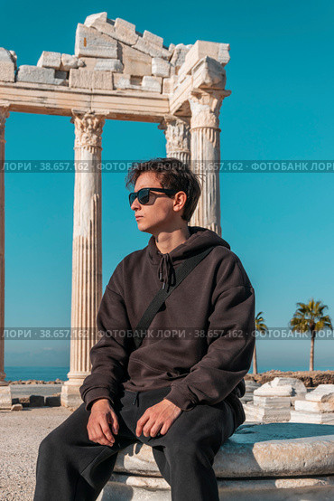 A teenager in a brown suit sits thoughtfully against the ruins of the Temple of Apollo in Side Turkey. Стоковое фото, фотограф Ярославский Максим / Фотобанк Лори