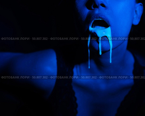 A thick white liquid flows down the lips of a young European girl. Dripping down. Ultraviolet, blue light. Close-up portrait. Spit out. Стоковое фото, фотограф Михаил Решетников / Фотобанк Лори