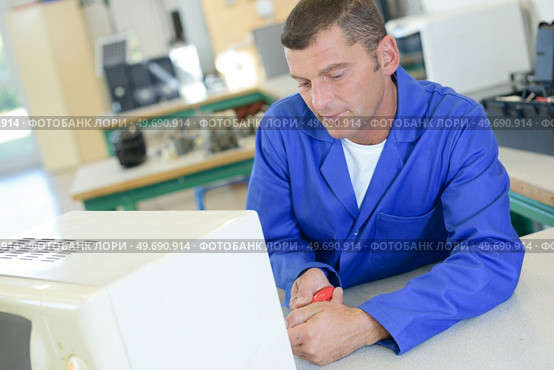 a tired technician fixing an oven. Стоковое фото, агентство Ingram Publishing / Фотобанк Лори