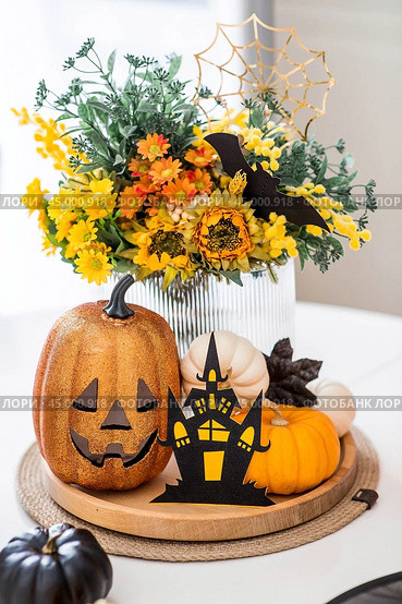 A vase of flowers, pumpkins and a scary castle with a witch on the background of a Scandi-style white kitchen interior. The concept of home and comfort. Autumn decor for Halloween. Стоковое фото, фотограф Photojuli / Фотобанк Лори