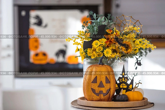 A vase of flowers, pumpkins and a scary castle with a witch on the background of a Scandi-style white kitchen interior. The concept of home and comfort. Autumn decor for Halloween. Стоковое фото, фотограф Photojuli / Фотобанк Лори