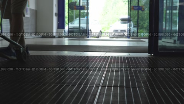 A view from inside a commercial building showing an entrance area where vehicles are parked outside, capturing the transition from indoors to outdoors. Стоковое видео, видеограф Владимир Федоров / Фотобанк Лори