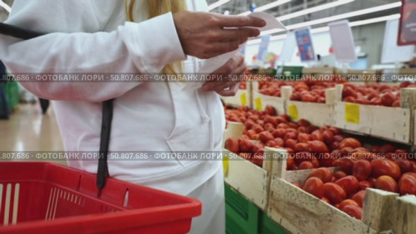 A woman in a supermarket looks at a receipt from purchases. Стоковое видео, видеограф Igor Skripachev / Фотобанк Лори