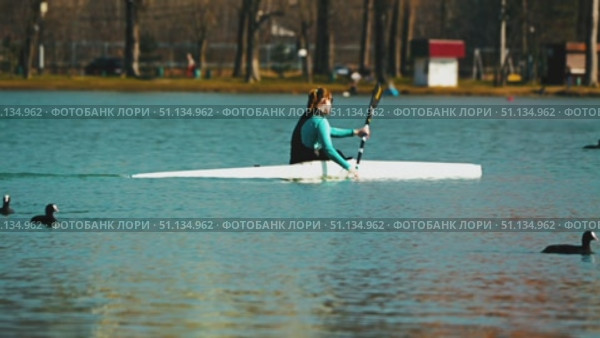 A woman kayaking on a serene lake. Athletes training on open water. Birds flying overhead, adding dynamics. Water sports. Krasnodar, Russia, March 3, 2025. Редакционное видео, видеограф Воловодов Владимир / Фотобанк Лори