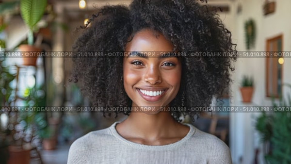 A woman with curly hair beams with joy in a lively setting filled with plants and natural light, radiating warmth and positivity. Стоковое AI-видео, аниматор Данила Большаков / Фотобанк Лори