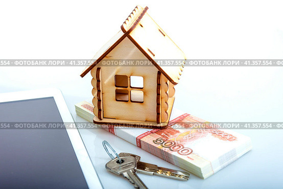 A wooden house as a symbol of real estate on a white background next to a tablet. Стоковое фото, фотограф Ярославский Максим / Фотобанк Лори