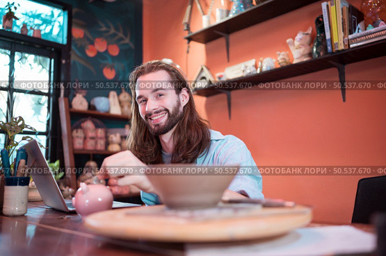 A young businessman owns a small pottery business. Are building themselves by saving money to expand their business in the future. Стоковое фото, агентство Ingram Publishing / Фотобанк Лори