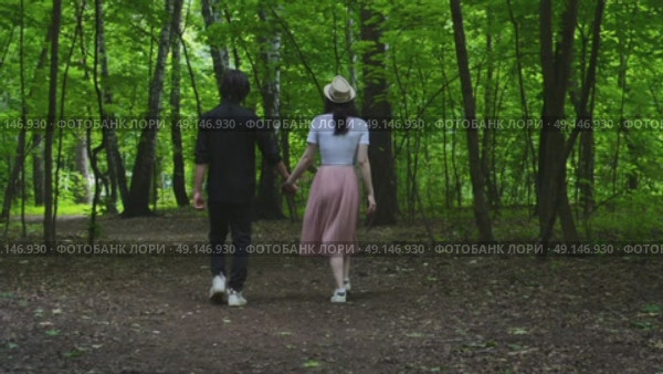 A young couple is walking along a forest path holding hands. Стоковое видео, видеограф Ярославский Максим / Фотобанк Лори