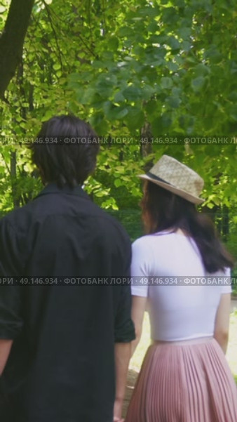 A young couple walks through a green summer park. They suddenly turn to the camera. Стоковое видео, видеограф Ярославский Максим / Фотобанк Лори