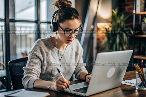 A young female freelance businessman in glasses and headphones is working on a laptop or shopping in an online store. The woman is writing something in a notebook. Стоковое AI-изображение, AI-художник Photojuli / Фотобанк Лори