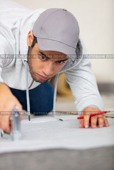 a young man is stapling an insulating layer to floor. Стоковое фото, агентство Ingram Publishing / Фотобанк Лори