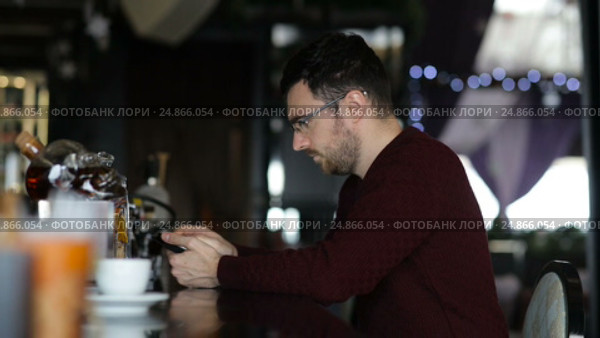 A young man uses tablet while sitting at the bar. Стоковое видео, видеограф Загородний Кирилл / Фотобанк Лори