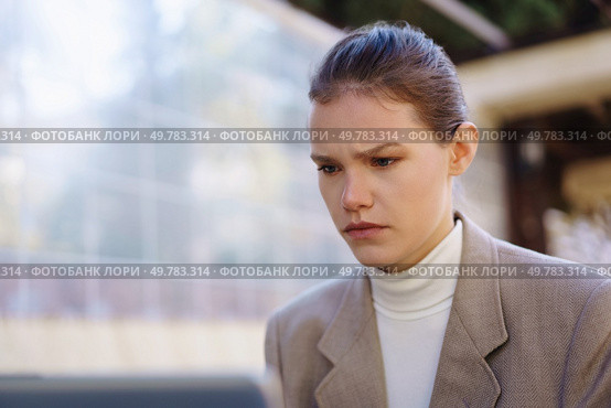 A young woman dressed in a contemporary and stylish outfit stands alone in a bustling urban environment while appearing pensive, lost in her deep thoughts amid a calm and serene backdrop. A contemplative woman is captured in an urban environment, showcasing her depth and beauty. Стоковое фото, агентство Ingram Publishing / Фотобанк Лори